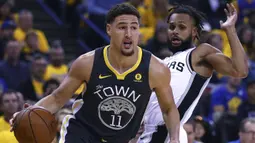 Aksi pemain Warriors, Klay Thompson (kiri) menggigiring bola melewati adangan pemain Spurs, Patty Mills pada game kedua putaran pertama playoffs NBA Basketball di Oracle Arena, Oakland, California, (16/4/2018). Warriors menang 116-101. (AP/Ben Margot)