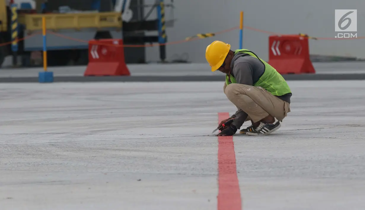 Pekerja menyelesaikan lajur pemandu pesawat di area apron Bandara Internasional Yogyakarta di Kab Kulon Progo, DI Yogyakarta, Selasa (23/4). Menurut rencana, khusus Bandara Internasional Yogyakarta ini akan mulai beroperasi pada 29 April mendatang. (Liputan6.com/Helmi Fithriansyah)