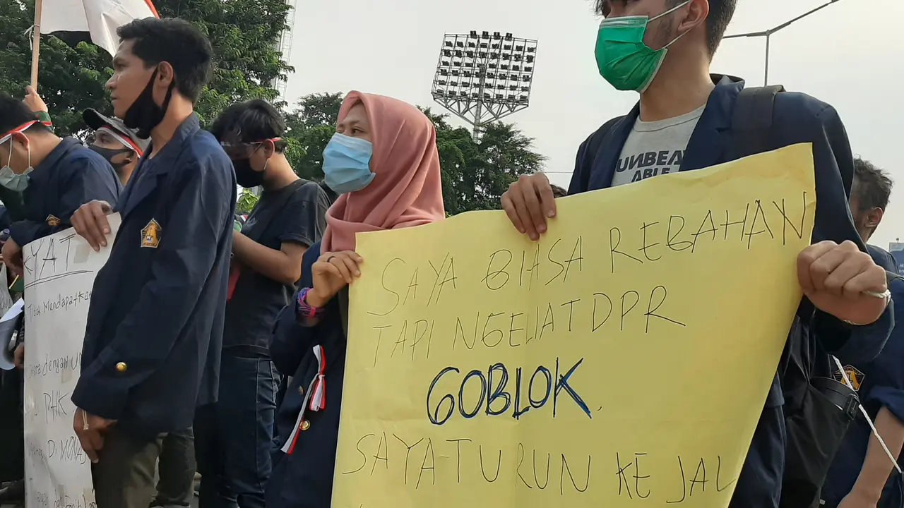 Puluhan mahasiswa membentuk barisan sambil membentangkan poster satire yang ditujukan untuk anggota DPR