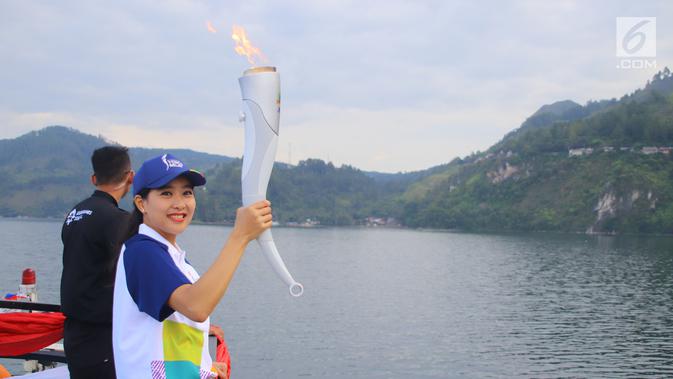 Artis Olivia Zalianty membawa obor Asian Games 2018 berkeliling Danau Toba di Sumatra Utara, Rabu (1/8). Obor Asian Games itu akan di bawa berlayar dengan kapal hias di Danau Toba dan bersepeda menuju pantai bebas Danau Toba. (Liputan6.com/Reza Perdana)