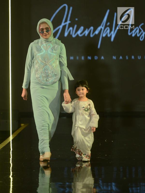 Seorang model berjalan bersama model cilik mengenakan busana rancangan Dhienda Nasrul pada hari ketiga Jakarta Modest Fashion Week di Gandaria City, Sabtu (28/7). Acara fashion ini diselenggarakan dari 26 hingga 29 Juli. (Kapanlagi.com/Bayu Herdianto)