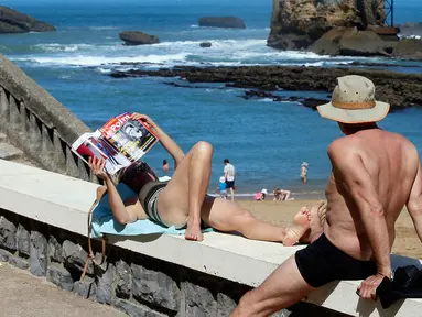 Seorang wanita membaca majalah saat berjemur di pantai Port Vieux, (Old Seaport) di Biarritz, barat daya Prancis, (19/4). Suhu di Prancis barat daya telah mencapai 27 derajat Celcius (80,6 Fahrenheit). (AP Photo / Bob Edme)