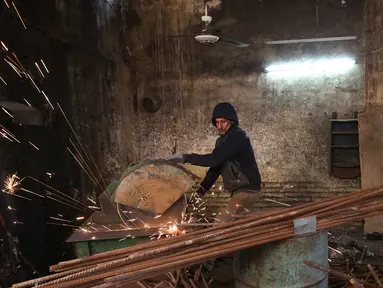 Seorang pekerja memotong besi di sebuah bengkel di Baghdad, Irak (20/2). Para pandai besi ini bekerja untuk membuat pasak tenda dan alat-alat pertanian. (AFP Photo/Ahmad Al-Rubaye)