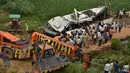 Warga dan polisi menyaksikan bus tingkat yang rusak usai mengalami kecelakaan di jalan bebas hambatan di Agra, India, Senin (8/7/2019). Kecelakaan terjadi sekitar pukul 04.15 waktu setempat saat bus melakukan perjalanan dari Lucknow menuju New Delhi. (Pawan Sharma/AFP)