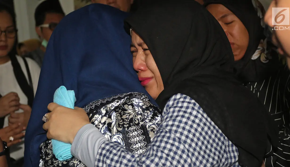 Kesedihan Retno Utami, istri Kepala Pusat Data Informasi dan Humas BNPB Sutopo Purwo Nugroho saat peti jenazah tiba di rumah duka di Raffles Hils, Depok, Minggu (7/7/2019). Sutopo meninggal dunia di China pada saat menjalani pengobatan kanker paru-paru yang dideritanya (Liputan6.com/Herman Zakharia)