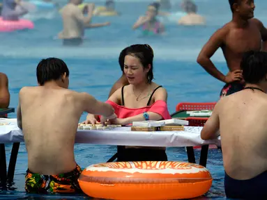 Sejumlah orang bermain catur di dalam kolam renang saat cuaca panas melanda wilayah Chongqing di Tiongkok, Rabu (2/8). Tiongkok saat ini dilaporkan sedang mengalami cuaca panas dengan suhu di beberapa daerah hampir mencapai 40 derajat celcius. (STR / AFP)