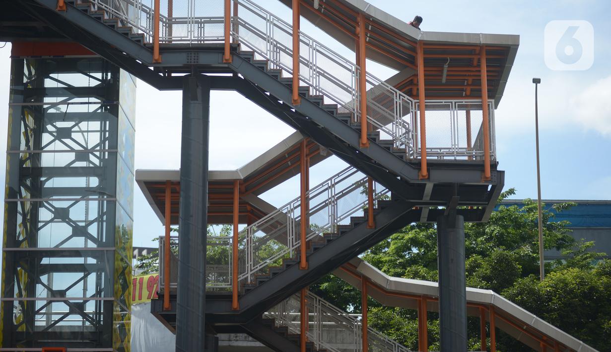 Pekerja terlihat di atas atap jembatan penyeberangan orang (skywalk) yang menghubungkan Stasiun Kebayoran dengan Halte Transjakarta di Kebayoran Lama, Jakarta, Jumat (6/1/2023). Skywalk sepanjang 450 meter tersebut untuk memudahkan mobilitas penumpang Transjakarta atau KRL yang beralih moda transportasi. (merdeka.com/Imam Buhori)
