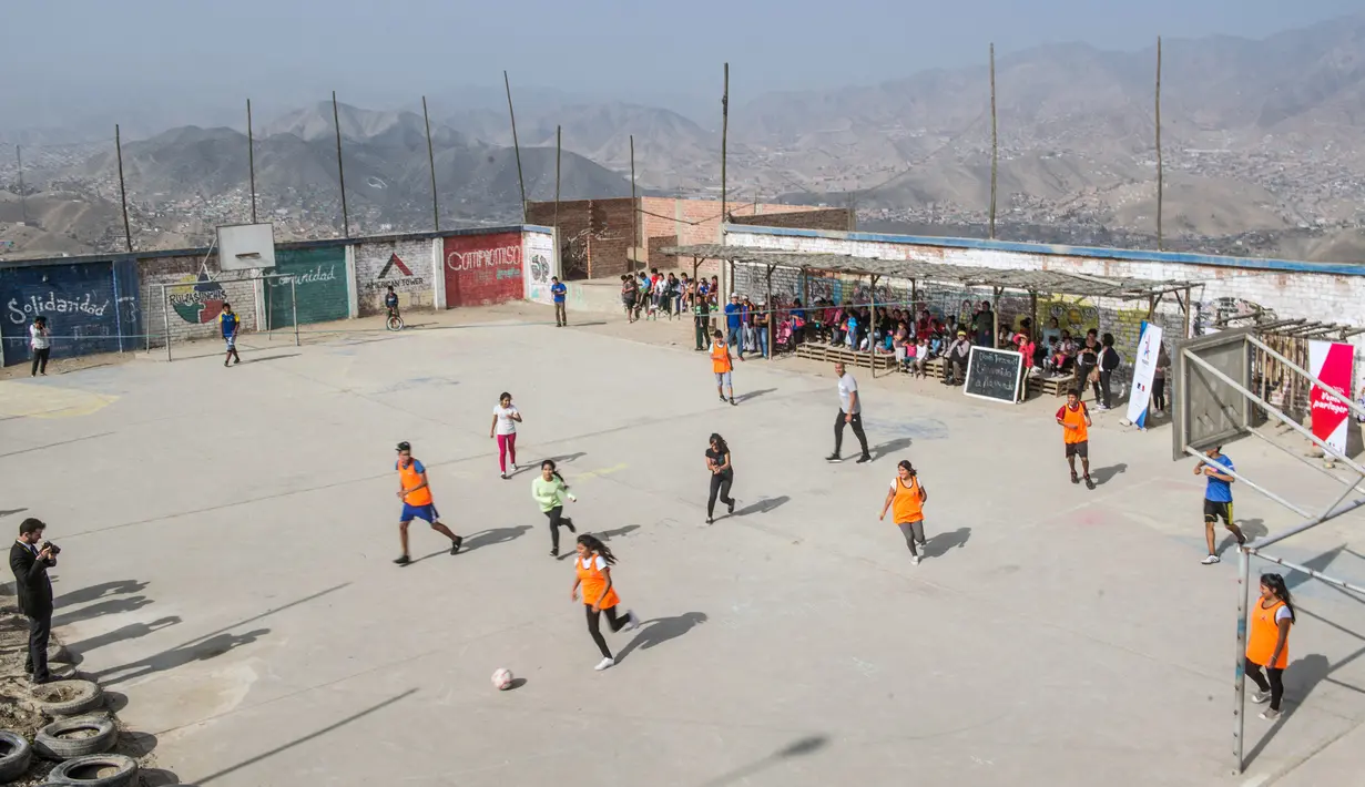 Sejumlah anak berebut bola saat bermain bersama David Trezeguet di komunitas San Pablo Mirador, Peru (13/7). (AFP Photo/Ernesto Benavides)