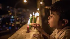 Seorang anak menyalakan lilin selama Hari Lilin Kecil di Medellin, Kolombia (7/12). Hari Lilin Kecil (bahasa Spanyol : Día de las Velitas) adalah salah satu dari hari raya tradisional yang paling dirayakan di Kolombia. (AFP Photo/Joaquin Sarmiento)