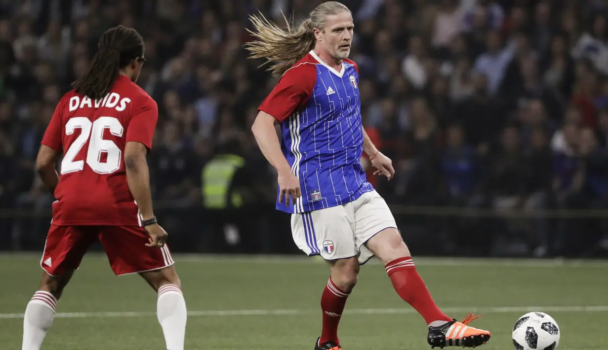 Gelandang Emmanuel Petit menggiring bola dari kawalan Edgar Davids saat pertandingan tim Prancis 98 dengan tim FIFA 98 di Arena U, Paris (12/6). Pertandingan ini memperingati 20 tahun kemenangan Prancis di Piala Dunia 1998. (AFP Photo/Thomas Samson)