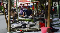 Pedagang ikan bandeng melayani pembeli di kawasan Rawa Belong, Jakarta Barat, Rabu (10/2/2021). Para pedagang ikan bandeng berdagang di pinggir jalan dan menjajakan kapada setiap pengendara yang melintas. (Liputan6.com/Johan Tallo)