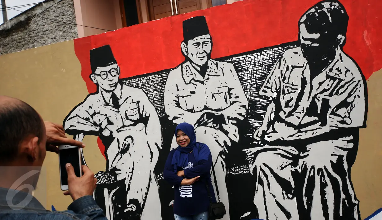 Warga berfoto di depan gambar Tiga Bapak Bangsa di Lapangan Kebagusan, Jakarta, Rabu (15/2). Jelang menggunakan hak pilihnya pada Pilkada, Ketua Umum PDI-P Megawati Soekarnoputri menggoreskan tinta pada salah satu gambar. (Liputan6.com/Helmi Fithriansyah)