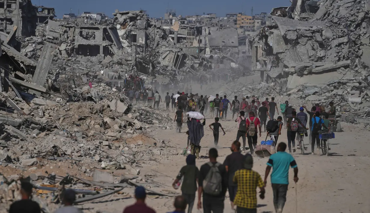 Pengungsi Palestina berjalan melewati bangunan-bangunan yang hancur saat mereka kembali ke rumah mereka di kawasan Zeitoun, Kota Gaza, pada Jumat 10 Oktober 2025, setelah Israel dan Hamas sepakat untuk menghentikan sementara perang mereka dan membebaskan sandera yang tersisa. (AP Photo/Jehad Alshrafi)