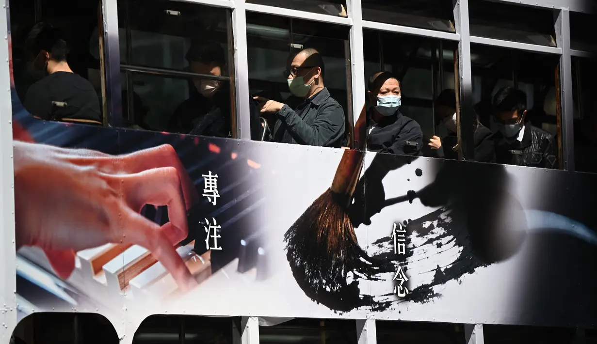 Orang-orang naik trem memakai masker di Hong Kong pada 27 Februari 2023. Pemimpin Hong Kong John Lee telah berharap untuk menghapus aturan penggunaan masker setelah gelombang musim dingin berakhir. (AFP/Peter Parks)