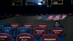 Seorang pria yang memakai masker menunggu di dalam bioskop Cineteca Nacional saat pelonggaran pembatasan di Mexico City, Rabu (12/8/2020). Setelah ditutup hampir lima bulan akibat Corona, bioskop di ibu kota Meksiko dibuka kembali dengan kapasitas 30 persen. (ALFREDO ESTRELLA/AFP)