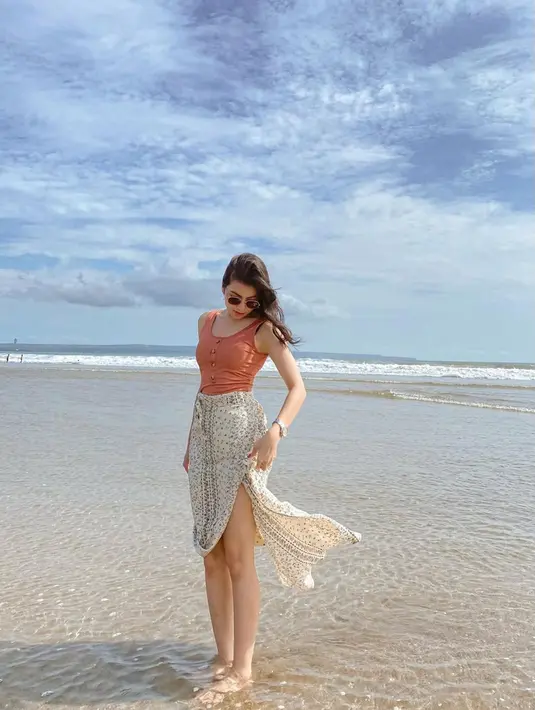 Gaya candid Shania Gracia saat di pantai ini bikin para penggemarnya jatuh hati. Aura kecantikan member yang masuk senbatsu single Flying High kian terpancarkan dengan baju tanpa lengan. Momen Gracia menikmati syahdunya pantai ini tuai atensi para penggemarnya. (Liputan6.com/IG/@jkt48gracia)