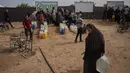 Keterbatasan bahan pangan, air bersih, serta padatnya lokasi pengungsian menciptakan kondisi rawan kelaparan dan penyakit. Tampak dalam foto, seorang wanita Palestina membawa jerigen berisi air yang dikumpulkan dari pabrik desalinasi, Khan Younis, Jalur Gaza selatan, Jumat 6 Februari 2026. (AP Photo/Abdel Kareem Hana)