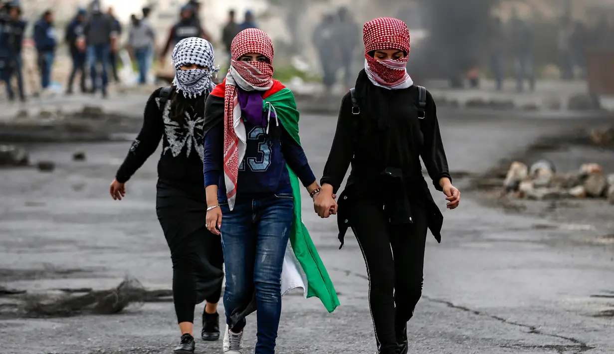 Wanita Palestina berjalan selama bentrokan dengan tentara Israel dalam demonstrasi untuk memperingati Hari Tanah di Tepi Barat, Sabtu (30/3).(Photo by ABBAS MOMANI/AFP)