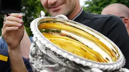 Ekspresi Roger Federer saat memegang trofi Australian Open 2017 di Carlton Gardens di Melbourne, Australia (30/1). Kemenangan Federer di Australian Open 2017 membuat dirinya meraih gelar ke-18 Grand Slam. (AP Photo / Aaron Favila)