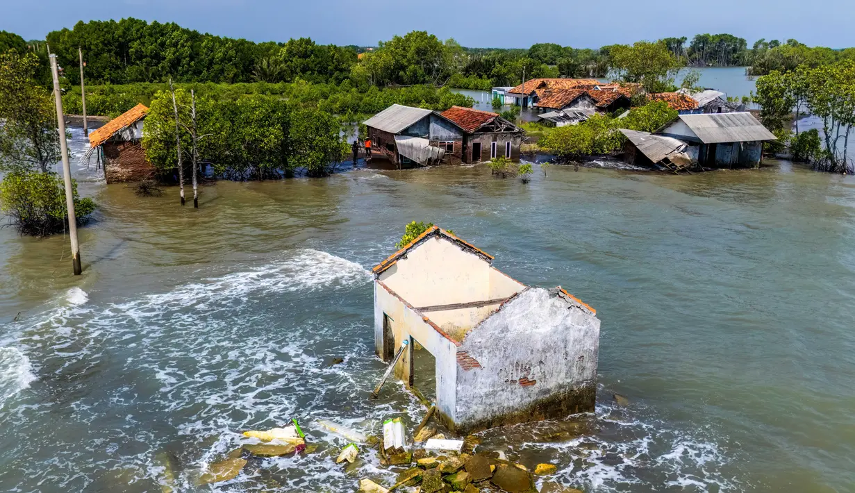 Ancaman tenggelamnya wilayah pesisir utara Jawa Tengah disebabkan oleh dua faktor utama, penurunan muka tanah (land subsidence) akibat penyedotan air tanah berlebihan serta kenaikan permukaan air laut yang diperparah oleh perubahan iklim global. Tampak dalam foto yang diambil pada 29 Juli 2025 menunjukkan pemandangan udara rumah-rumah yang terbengkalai dan sebagian terendam air, yang hilang akibat kenaikan pasang surut akibat perubahan iklim, di Desa Semonet, Pekalongan, Jawa Tengah. (BAY ISMOYO/AFP)
