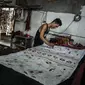 Seorang pekerja mensketsa batik di pabrik "batik" kain tradisional Indonesia di Sidoarjo, Jawa Timur (12/11/2019). UNESCO menetapkan batik sebagai karya agung lisan dan warisan budaya takbenda kemanusiaan. (AFP Photo/Juni Kriswanto)