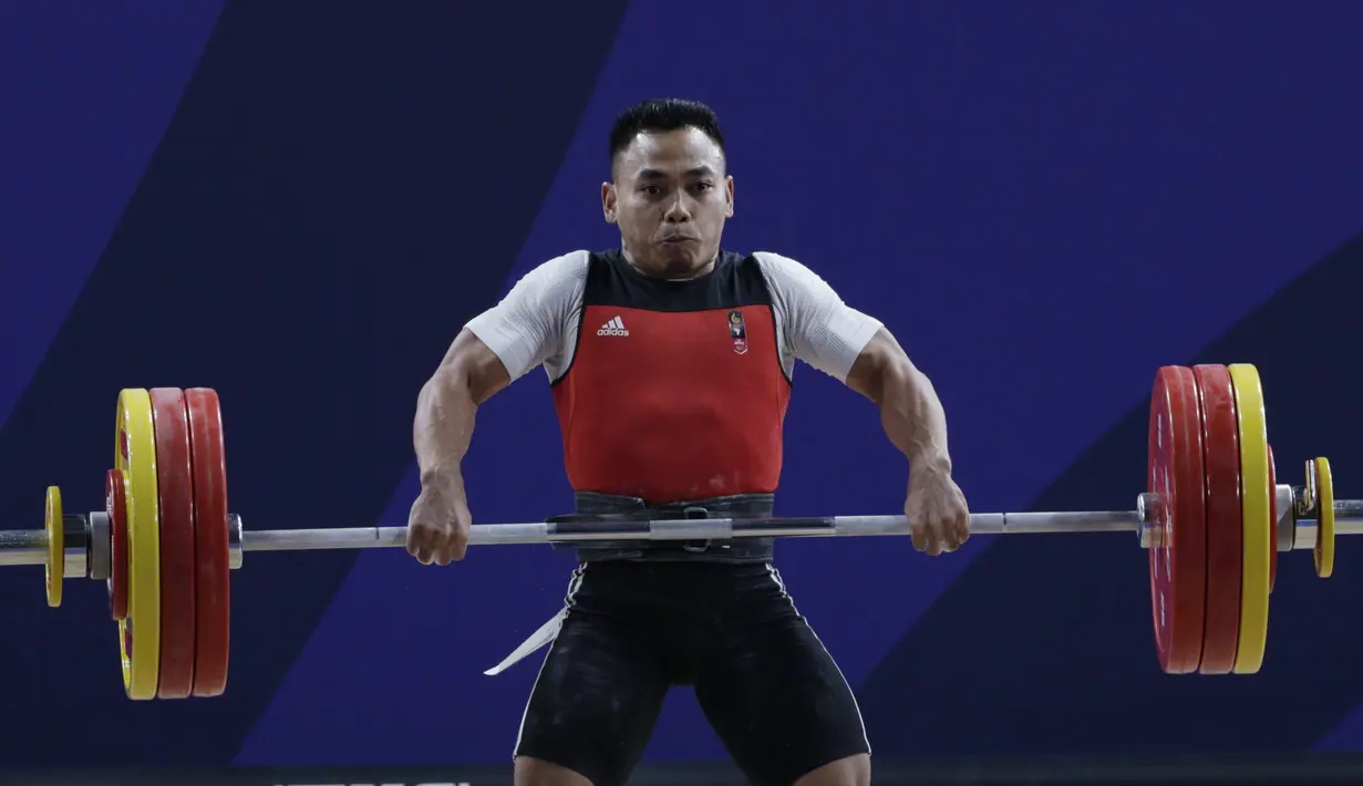Lifter Eko Yuli melakukan angkatan saat SEA Games 2019 cabang angkat besi nomor 61 kg di Stadion Rizal Memorial, Manila, Minggu (1/12). Dirinya meraih emas dengan total angkatan 309 kg. (Bola.com/M Iqbal Ichsan)