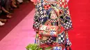 Seorang model berjalan di atas catwalk dengan membawa tas besar mirip tas pasar dan mengisinya dengan sayuran untuk koleksi Dolce & Gabbana Spring/Summer 2018 di Milan Fashion Week, Minggu (24/9). (AFP PHOTO / Andreas SOLARO)