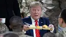 <p>Presiden Amerika Serikat Donald Trump mengangkat nampan makan malam saat mengunjungi Pangkalan Udara Bagram, Afghanistan, Kamis (28/11/2019). Kunjungan dadakan Trump pada hari Thanksgiving tersebut mengejutkan pasukan AS yang bertugas di Afghanistan. (AP Photo/Alex Brandon)</p>