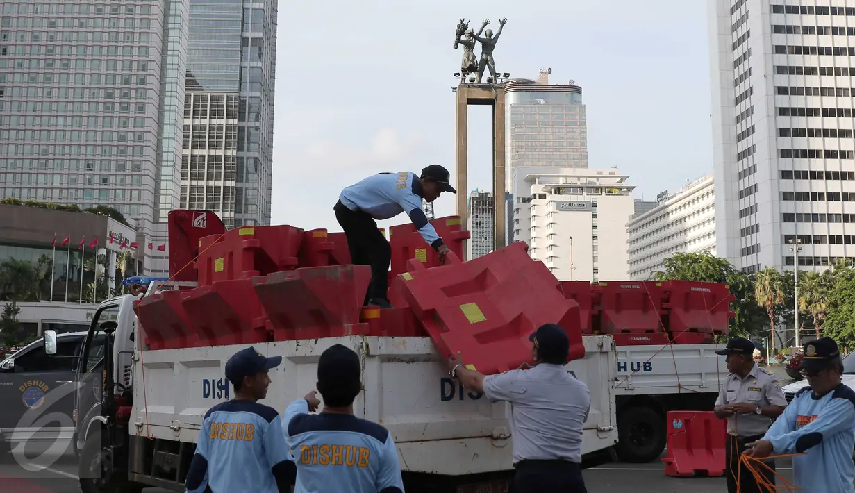 Petugas Dishub menurunkan pembatas jalan di kawasan Bundaran HI, Jakarta, (31/12). Hal ini dilakukan agar  perayaan tahun baru tidak dipusatkan di Bundaran Hotel Indonesia (HI) atau penyelenggaraan car free night.(Liputan6.com/Angga Yuniar)