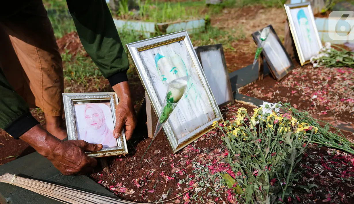 Sardi, pengurus makam merapikan pigura Vanessa Angel dan Bibi Ardiansyah di TPU Taman Makam Islam Malaka Blok D, Pesanggrahan, Jakarta, Senin (7/02/2022). Pihak Doddy Sudrajat diketahui sudah mengurus perizinan untuk memindahkan makam Vanessa Angel ke TPU Karet Bivak. (Liputan6.com/Fery Pradolo)