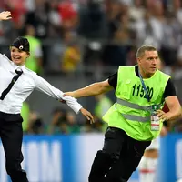 Seorang wanita menyusup masuk ke lapangan dalam laga final Piala Dunia 2018 antara Prancis dan Kroasia di Luzhniki Stadium, Minggu (15/7). Empat orang berseragam polisi menyusup masuk ke dalam lapangan. (AP/Martin Meissner)