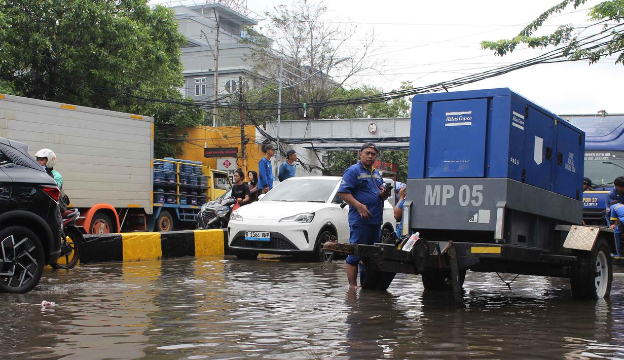 Sejumlah petugas dari Dinas Sumber Daya Air (SDA) DKI Jakarta melakukan upaya pemompaan air untuk mempercepat proses penanggulangan banjir. Tampak dalam foto, petugas Dinas Sumber Daya Air (SDA) DKI Jakarta menyalakan pompa air sebagai upaya penanggulangan genangan banjir yang belum surut di Jalan Gunung Sahari Raya atau tepat di depan Mangga Dua Square, Jakarta, Selasa (13/1/2026). (merdeka.com/magang/Rendi Saputra)