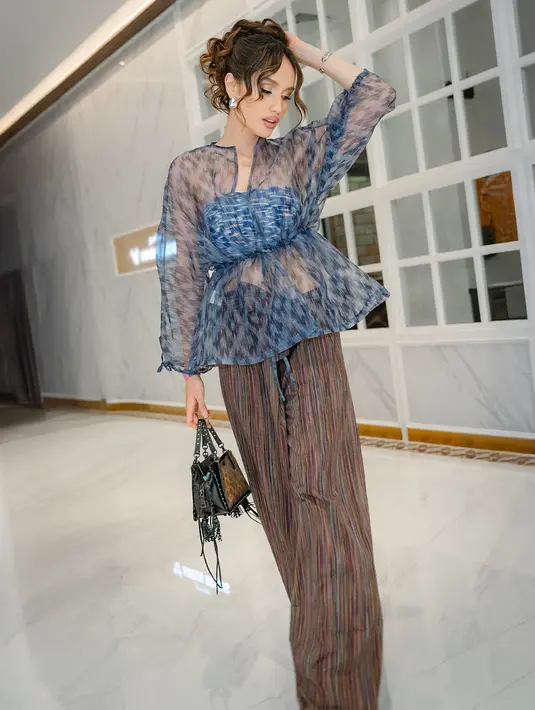 Hadir di PIFW 2025, Cina Laura kenakan bralette batik dengan outer baby doll transparan bermotif. Straight pants batik berwarna cokelat bikin tampilan Cinta terlihat makin edgy [@claurakiehl]