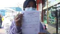 Pedagang memperlihatkan surat keterangan hasil tes di pusat perbelanjaan kawasan Cikarang, Kabupaten Bekasi, Kamis (27/05/2021). Pasca libur lebaran, Forkopimda Kabupaten Bekasi melakukan swab tes antigen kepada 202 pedagang guna mencegah penyebaran COVID-19. (Liputan6.com/Herman Zakharia)