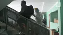 Paramedis berjalan dengan pasien positif COVID-19 di Puskesmas Jurumudi, Tangerang, Banten, Kamis (17/2/2022). Kasus positif COVID-19 di Kota Tangerang terus mengalami penurunan kasus dari 2000 kasus perhari menjadi 1000 kasus perhari. (merdeka.com/Arie Basuki)
