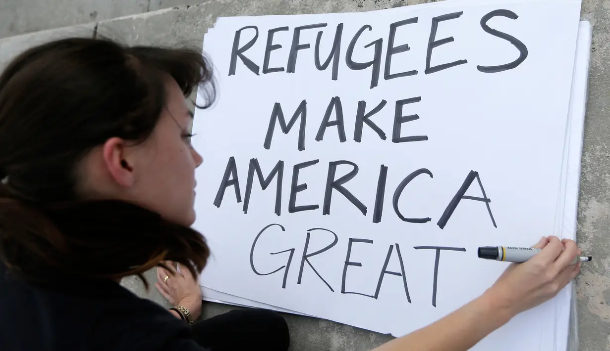 Seorang wanita mempersiapkan bahan untuk berunjuk rasa di pusat kota Miami, AS, Kamis (26/1). Pengunjuk rasa menolak kebijakan Presiden AS, Donald Trump yang membatasi warga Muslim masuk ke AS. (AP Photo / Alan Diaz)