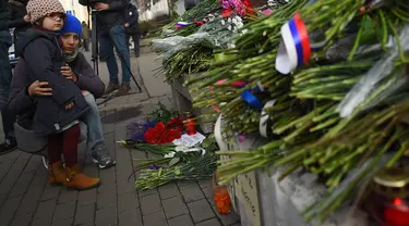 Warga Moskow melihat karangan bunga di luar Kedutaan Besar Prancis di Moskow, Sabtu (14/11/2015) . Karangan bunga tersebut untuk menghormati para korban serangan mematikan di Paris. (AFP Photo/Dmitry Serebryakovi)