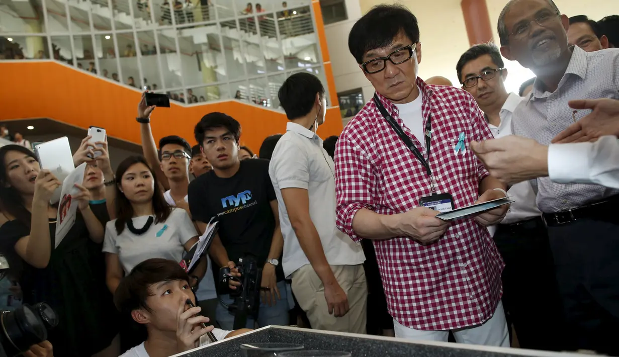 Jackie Chan menyempatkan diri untuk melihat sebuah pameran saat peluncuran aplikasi mobile game anti-narkoba 'Aversion', Singapura, Kamis (7/5/2015). Aplikasi ini sebagai kepedulian tentang bahaya penyalahgunaan narkoba. (Reuters/Edgar Su)