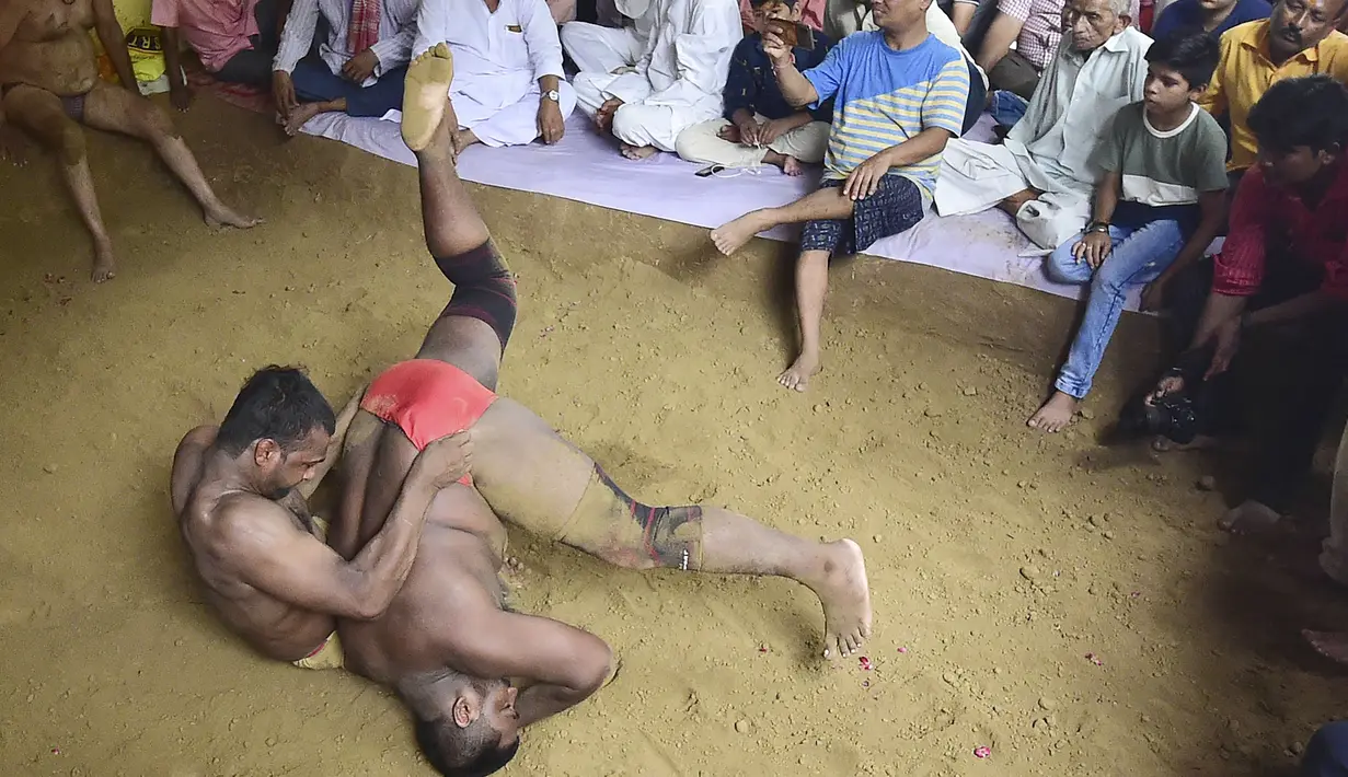 Pegulat beraksi dalam pertandingan gulat tradisional di klub gulat Loknath Vyayamsala di Prayagraj, India, (21/8/2023). Acara tersebut untuk merayakan festival Hindu Nag Panchami. (AFP/Sanjay kanojia)