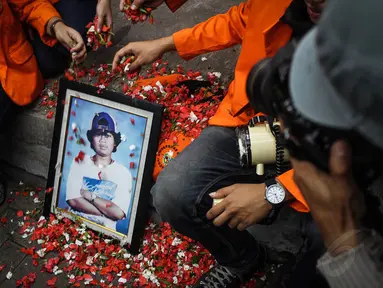 Sejumlah mahasiswa menabur bunga pada foto korban Tragedi Semanggi I, di depan Kampus Unika Atma Jaya, Jakarta, Kamis (13/11/2014). (Liputan6.com/Faizal Fanani)
