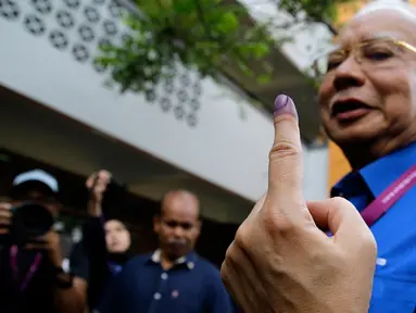 Perdana Menteri Malaysia, Najib Razak menunjukan jari yang telah diberi tinta usai memberikan hak suaranya di Pekan, Pahang, Rabu (9/5). Pemilu ini pertarungan antara PM Najib yang sudah berkuasa sejak 2009, melawan Mahathir Mohamad. (AP/Aaron Favila)