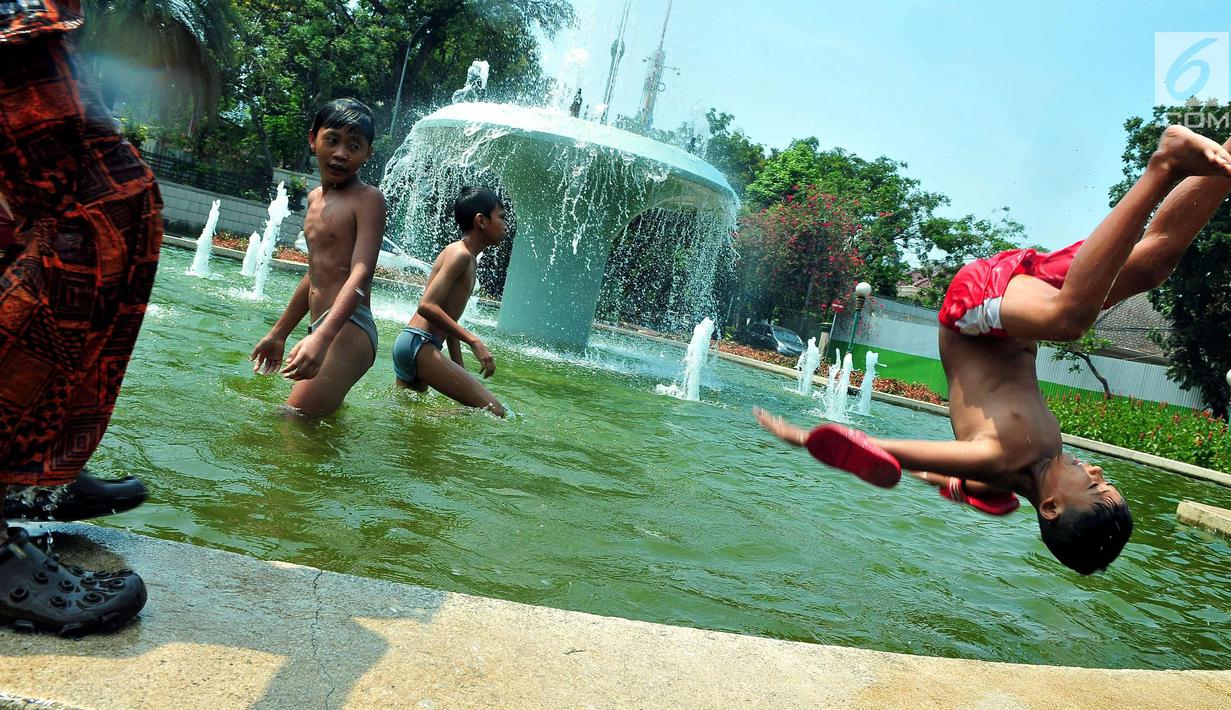 Seorang anak melompat di bundaran air mancur Jalan Teuku Umar, Jakarta Pusat, Sabtu (23/9). Cuaca panas ibu kota memaksa anak-anak menceburkan diri di kolam untuk menyejukkan badan. (Liputan6.com/Helmi Afandi)