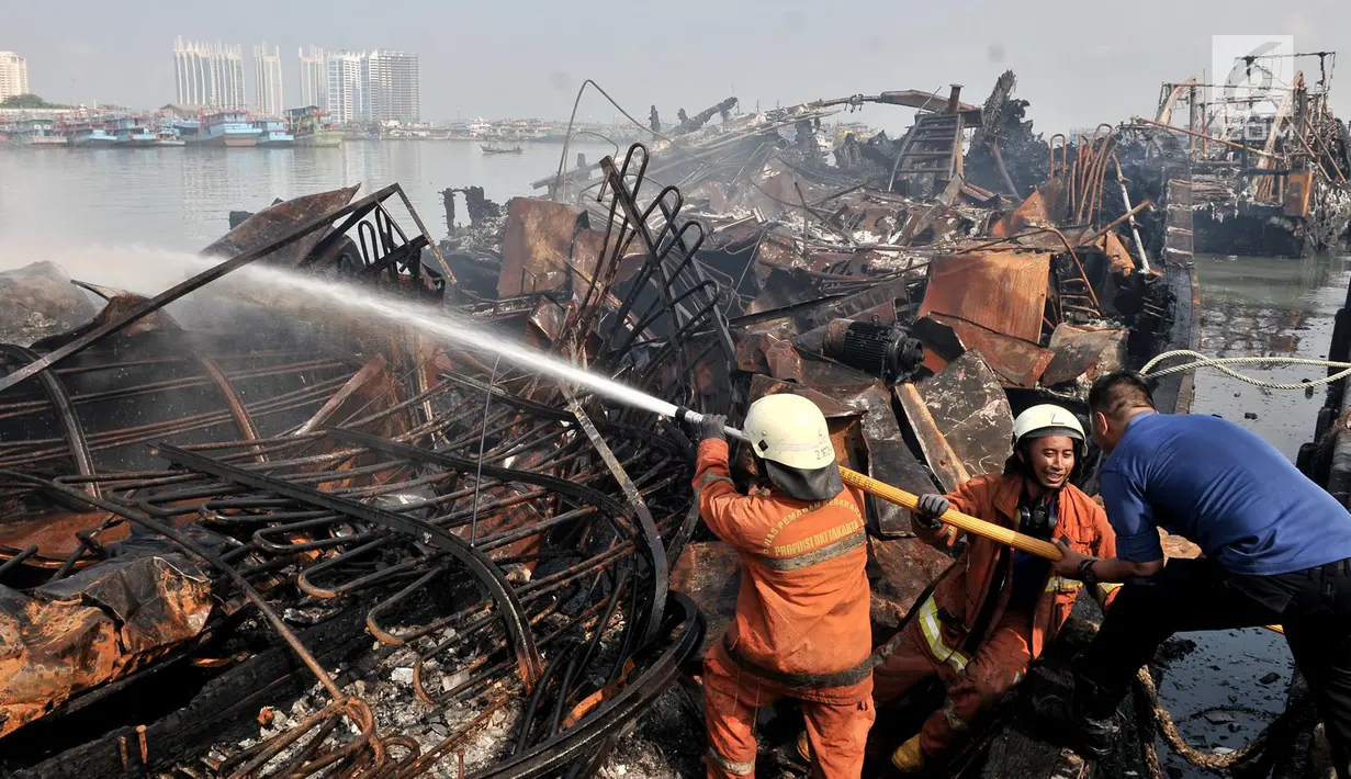 Petugas pemadam kebakaran melakukan pendinginan kapal yang ludes dilalap api di Pelabuhan Muara Baru, Jakarta, Minggu (24/2). Saat ini, polisi juga telah memeriksa tujuh saksi terkait kebakaran tersebut. (Merdeka.com/Iqbal Nugroho)