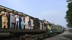 Warga Pakistan menaiki kereta api ke kampung halaman untuk merayakan Idul Adha, atau "Hari Raya Kurban," di Lahore, Pakistan, Kamis (7/7/2022). Selama hari raya, yang di sebagian besar tempat berlangsung selama empat hari, umat Islam menyembelih domba atau sapi dan membagikan sebagian dagingnya kepada orang miskin. (AFP/Arif Ali)