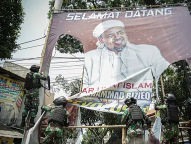 Anggota TNI mencopot paksa baliho Rizieq Shihab yang terpasang di sekitar kawasan Petamburan, Jakarta, Jumat (20/11/2020). Pencopotan dilakukan karena menyalahi aturan yang telah ditetapkan. (Liputan6.com/Faizal Fanani)