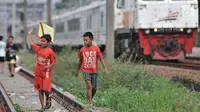 Anak-anak bermain layang-layang di rel kereta api kawasan Jakarta Timur, Kamis (3/1). Rel yang sering dilintasi kereta api tersebut sangat membahayakan diri mereka. (Merdeka.com/Iqbal Nugroho)