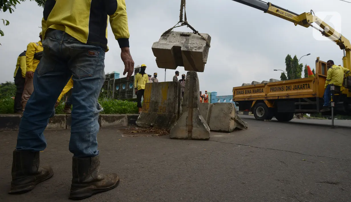 Petugas gabungan memindahkan beton pembatas dengan alat berat di Jalur Inspeksi Kanal Banjir Timur (KBT), Cipinang, Jakarta Timur, Kamis (30/12/2021). Kawasan KBT ditutup guna mencegah kerumunan warga yang hendak merayakan malam pergantian tahun. (merdeka.com/Imam Buhori)