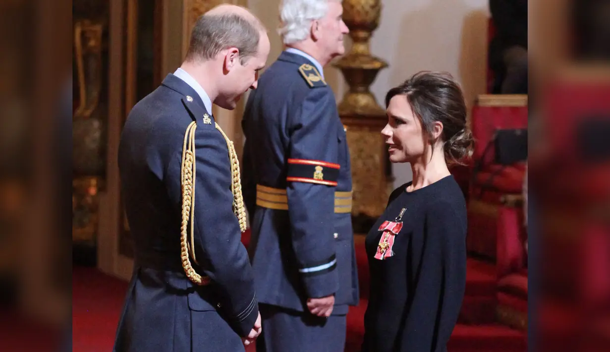 Victoria Beckham berbincang dengan Pangeran William sebelum menerima gelar Order of the British Empire (OBE) di Istana Buckingham di London, Inggris (19/4). Wanita 43 tahun itu ditemani sang suami saat menerima penghargaan tersebut. (Yui Mok / PA via AP)