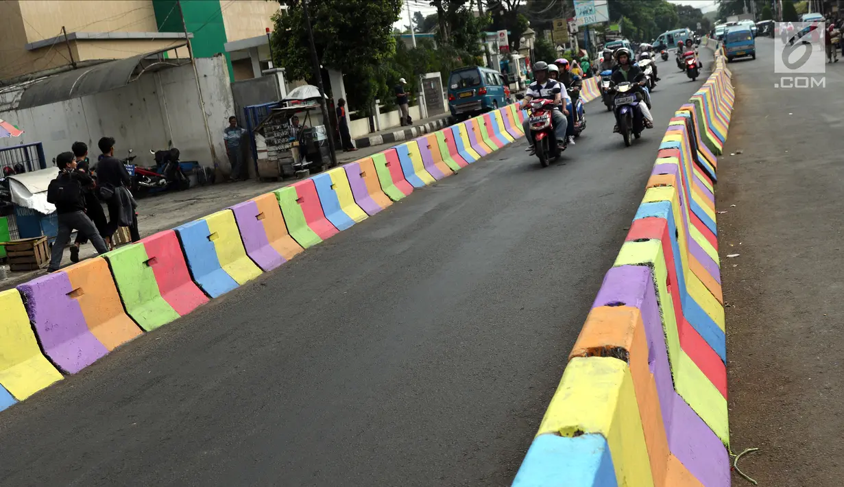 Pengendara motor melintasi di sisi pemisah jalan di Jalan Raya Ragunan sekitar Pasar Minggu, Jakarta, Selasa (24/7). Di kawasan ini pemisah jalan di cat warna warni sehingga terlihat lebih semarak. (Liputan6.com/Helmi Fithriansyah)
