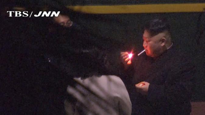 Sosok Kim Jong-un tertangkap kamera tengah merokok saat beristirahat di China dalam perjalanan menuju Vietnam (TBS TV via AP)